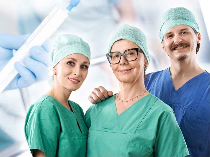 Drei Pflegefachkräfte im OP blicken in die Kamera