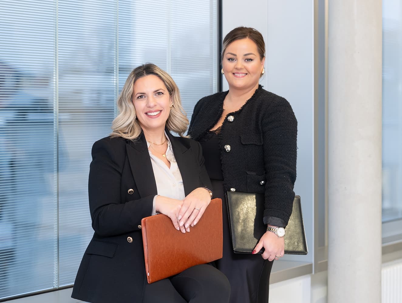 Zwei Frauen, die sich um das Integrations- und Anerkennungsmanagement kümmern, stehen im Krankenhausflur und blicken in die Kamera