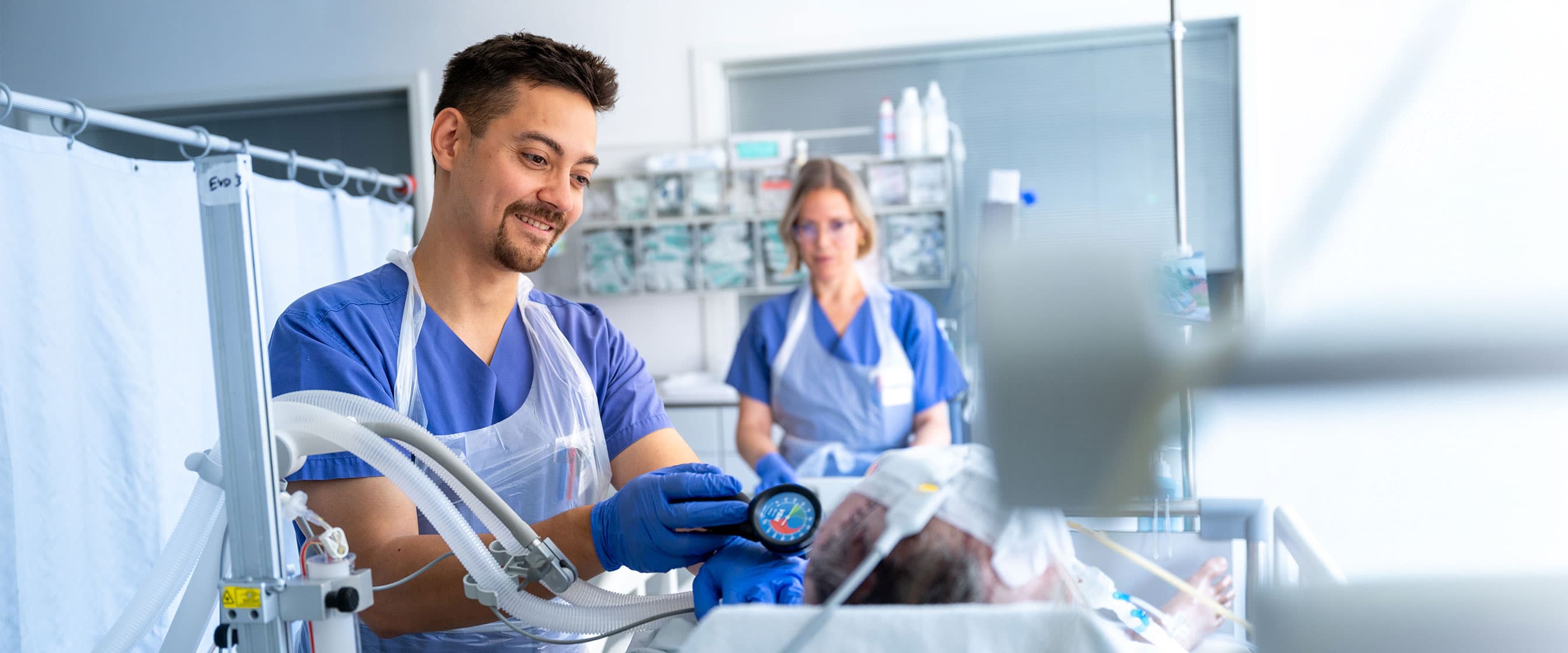 Ein Intensivpflegefachmann behandelt mit seiner Kollegin einen Patienten im Neurokopfzentrum