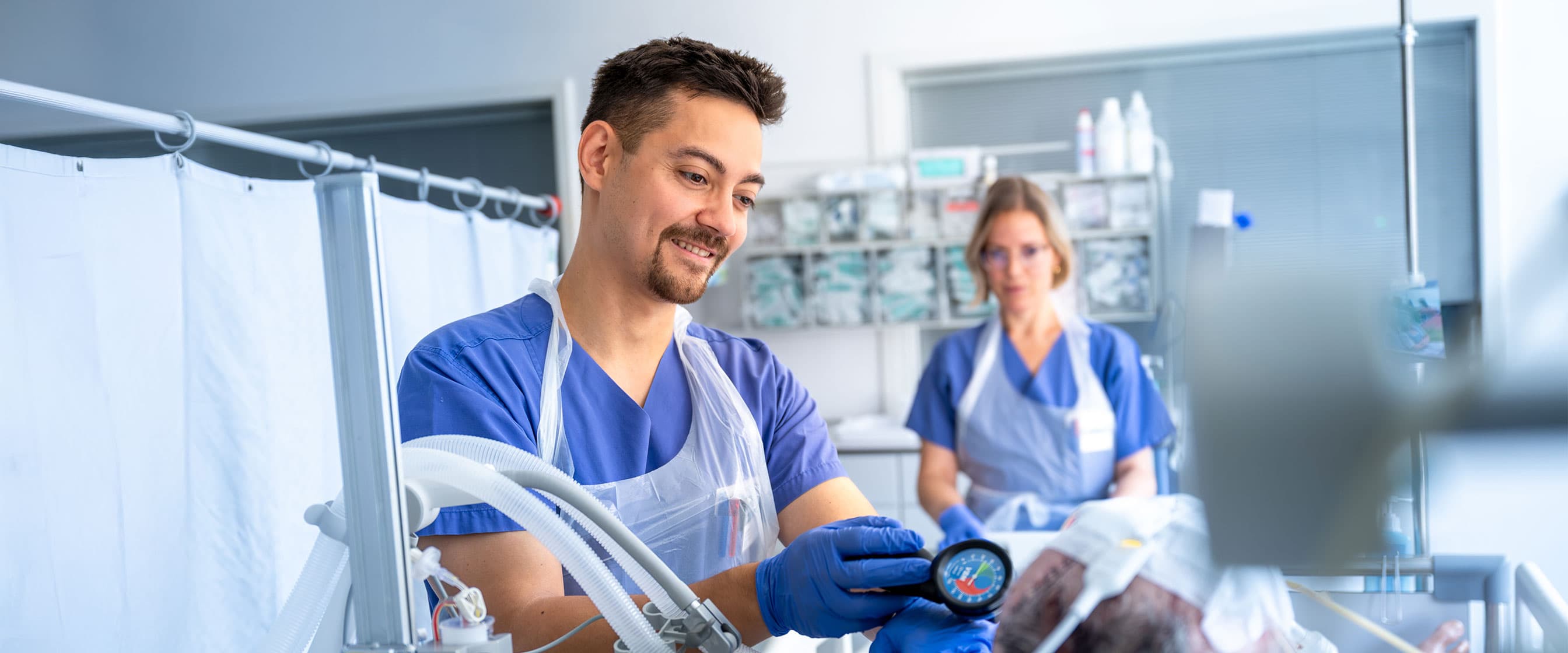 Ein Intensivpflegefachmann behandelt mit seiner Kollegin einen Patienten im Neurokopfzentrum