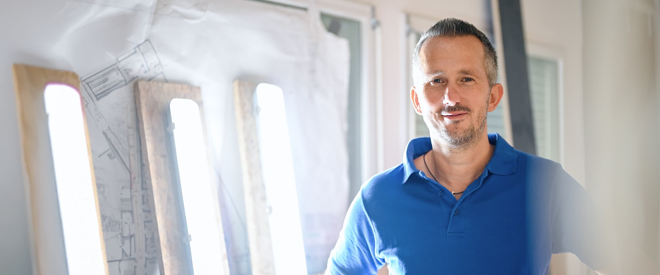 Antonio, ein Mitarbeiter aus dem Bereich Bau und Technik, steht auf einer Baustelle und blickt in die Kamera