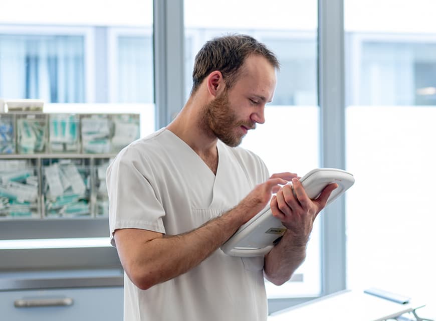 Ein Pflegefachmann gibt Daten in einem iPad zur Patientendokumentation ein