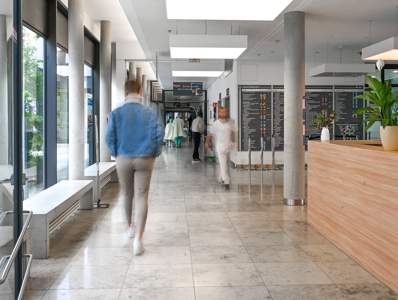 Mitarbeitende und Patieninnen und Patienten laufen durch einen Krankenhausflur