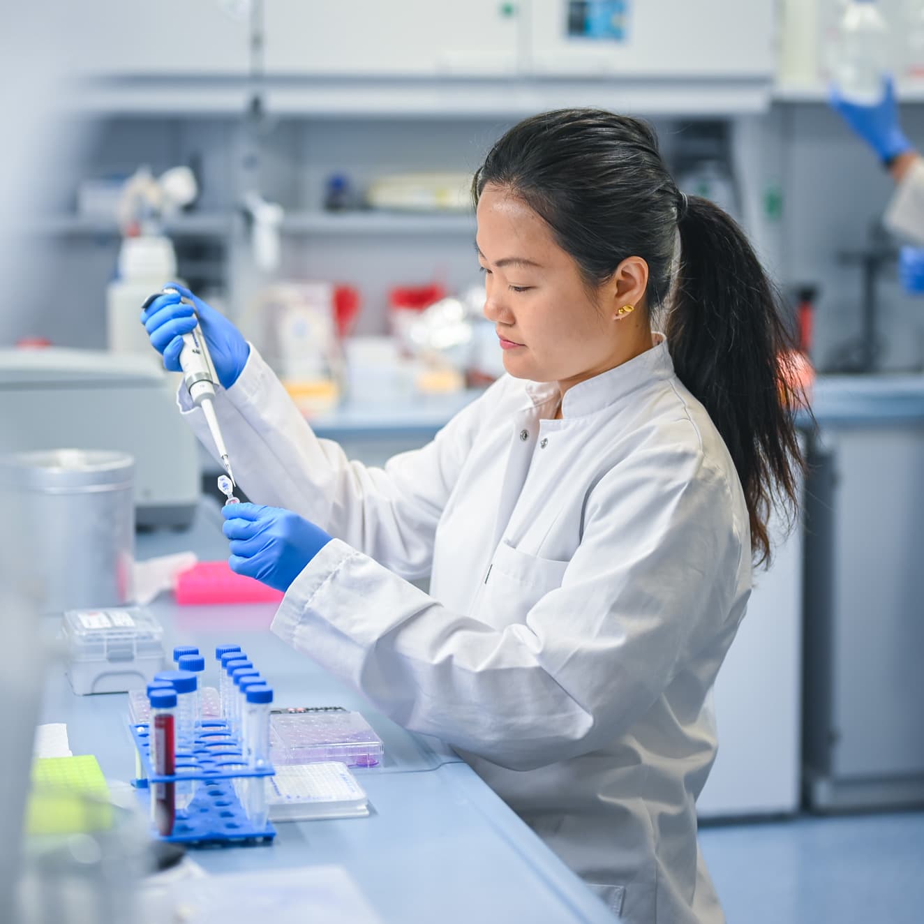 Eine Forscherin steht im Labor und arbeitet an Reagenzgläsern