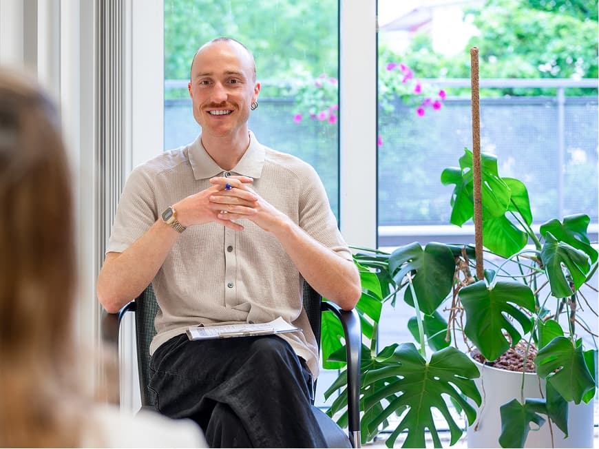 Ein Therapeut sitz in einer Gruppentherapie und hört einer Patientin zu