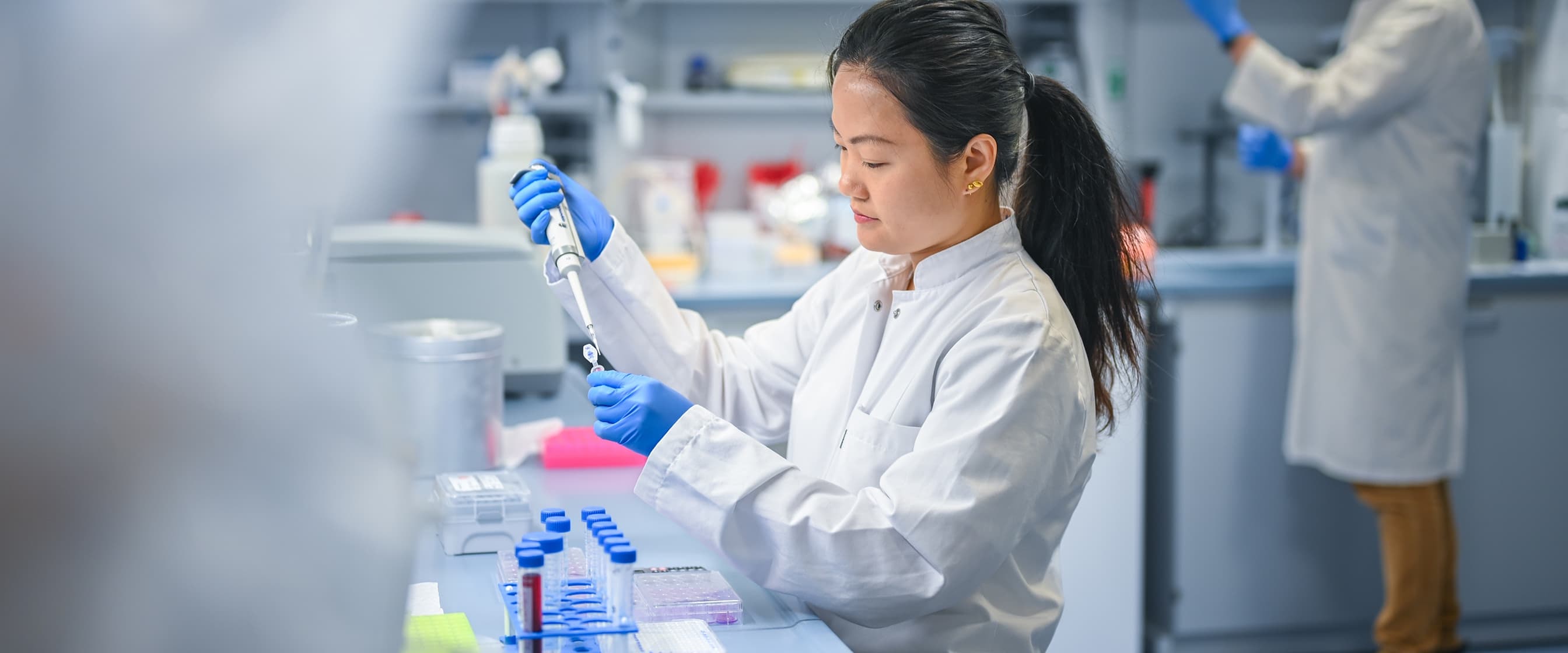 Eine Forscherin und ein Forscher stehen im Labor und arbeiten an Reagenzgläsern