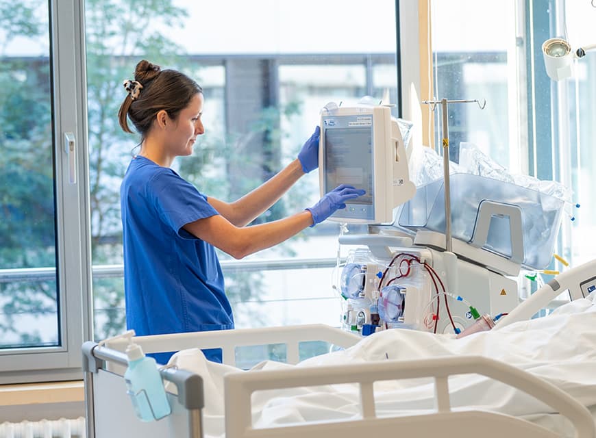 Ein Pflegefachmann behandelt einen Patienten in seinem Krankenbett auf der Intensivstation