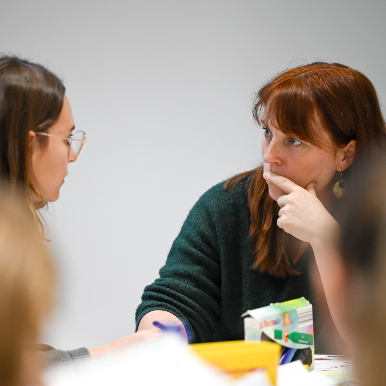 Eine Praxisanleiterin erklärt einer Gruppe von Pflegefachkräften etwas während einer Fortbildung im Klassenraum